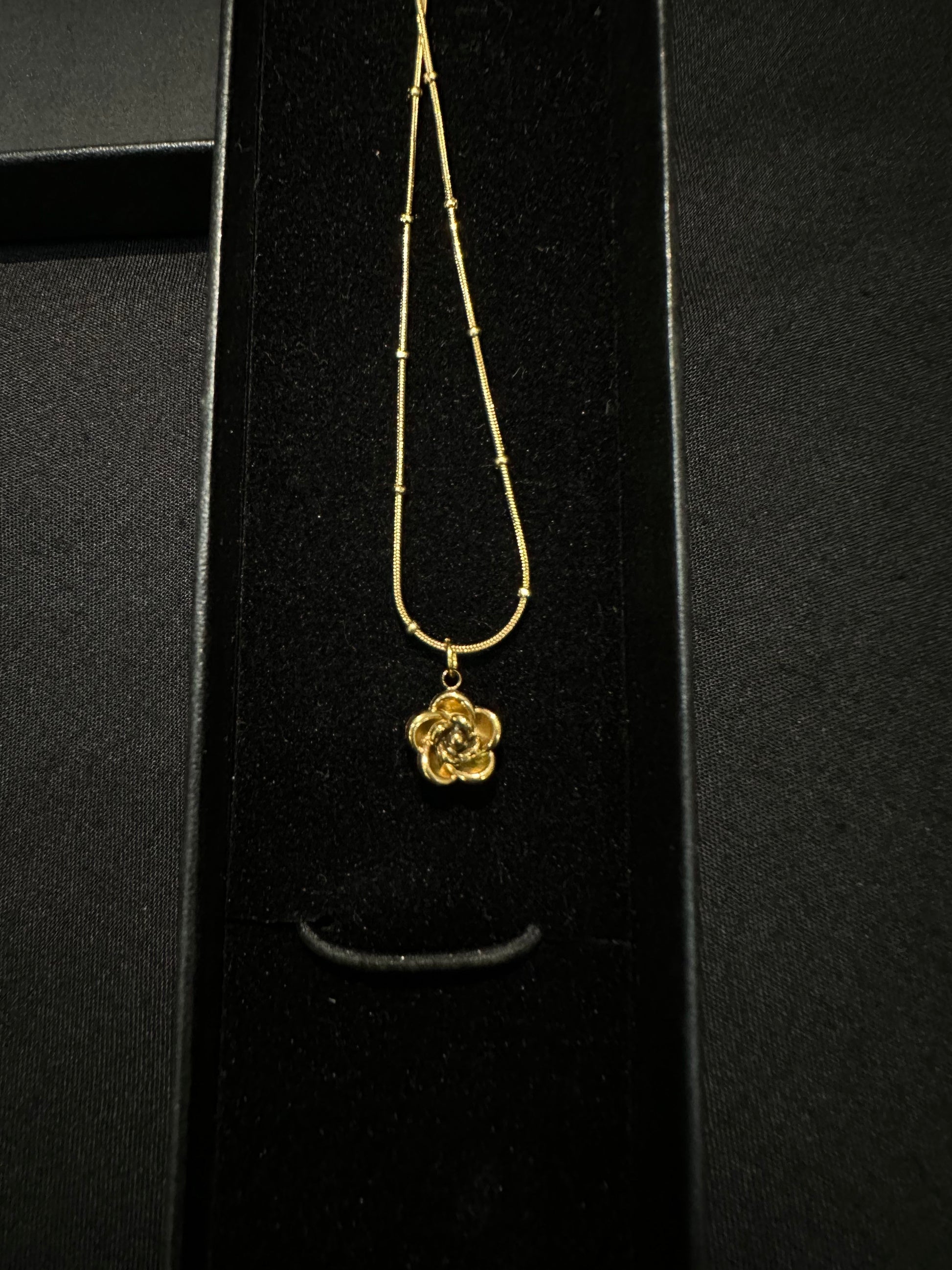 Golden Bloom pendant necklace by Zyro featuring a floral design with a polished gold finish, displayed on a white background.