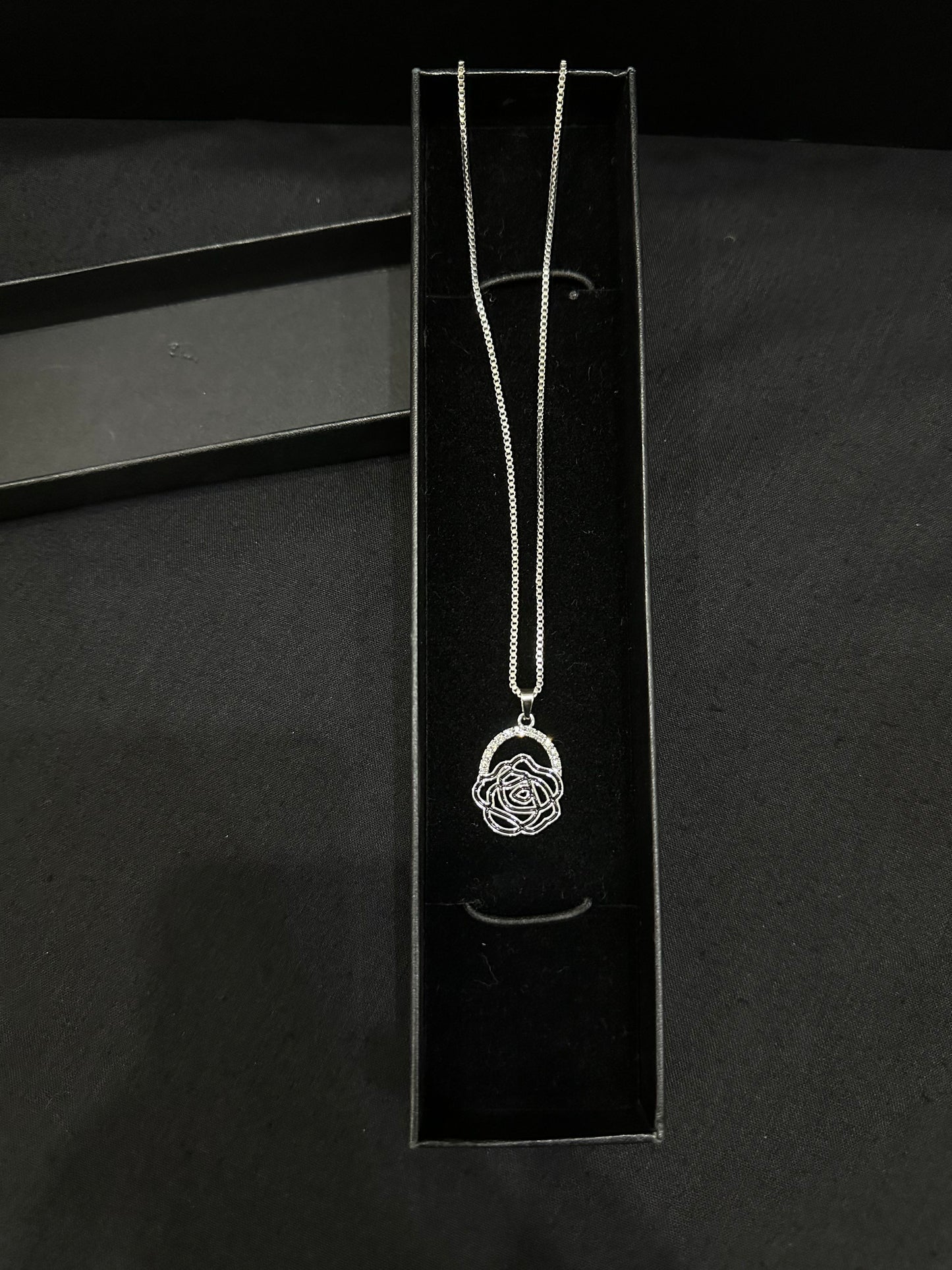 Silver rose pendant by Zyro featuring a detailed, polished rose design on a delicate chain, close-up view.