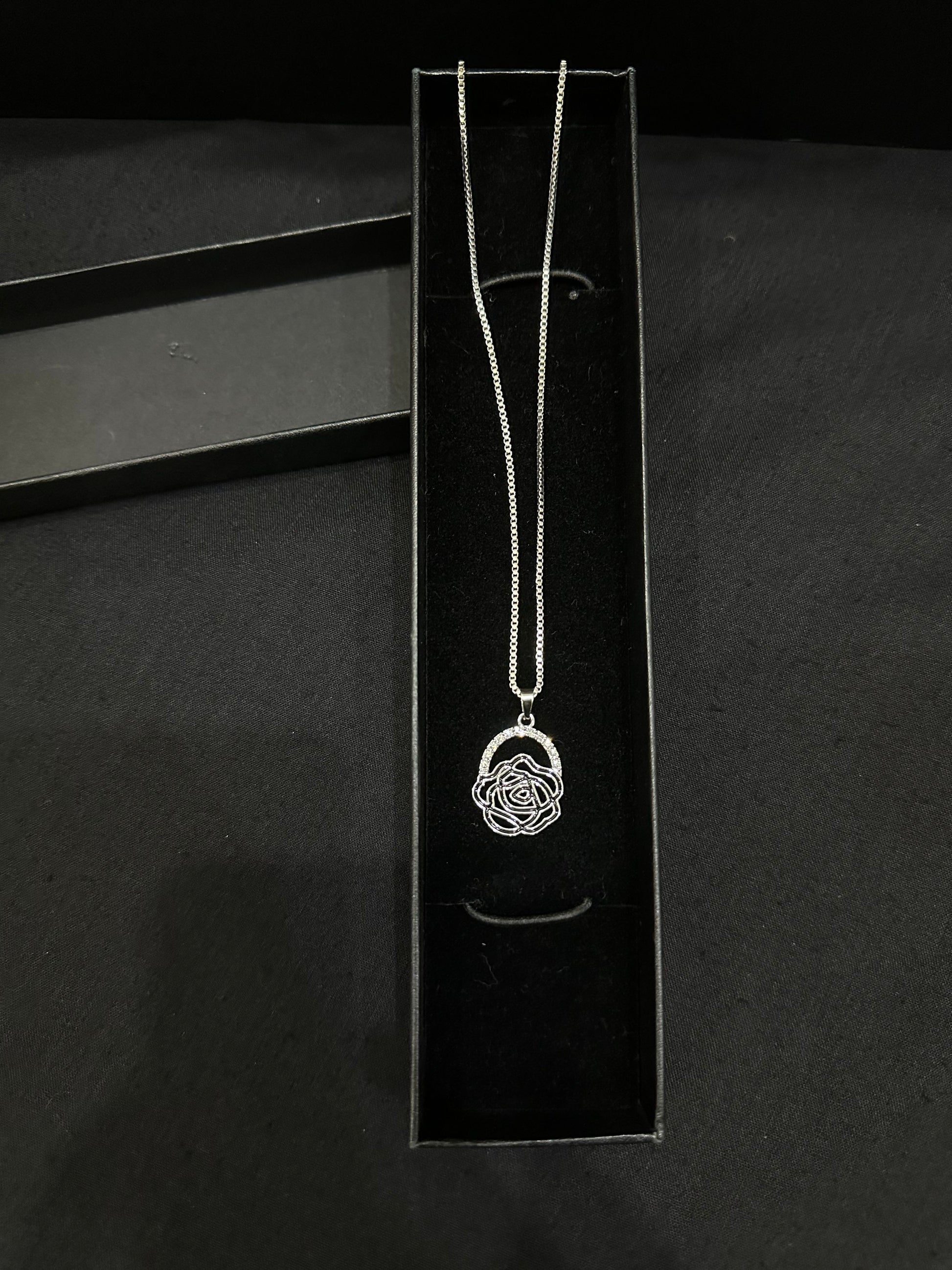 Silver rose pendant by Zyro featuring a detailed, polished rose design on a delicate chain, close-up view.
